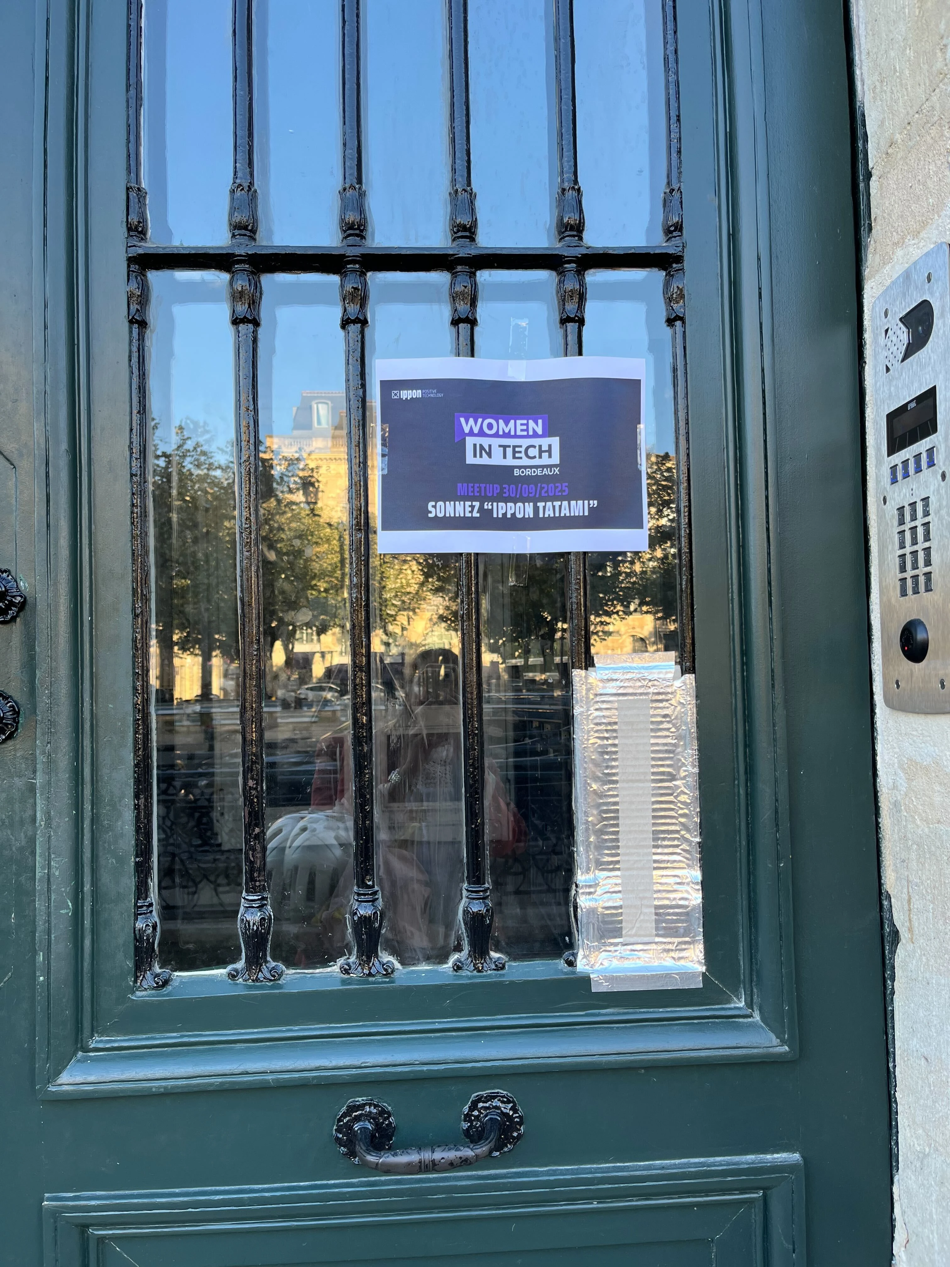 Affiche Women in Tech Bordeaux sur la porte d’entrée d’un immeuble.